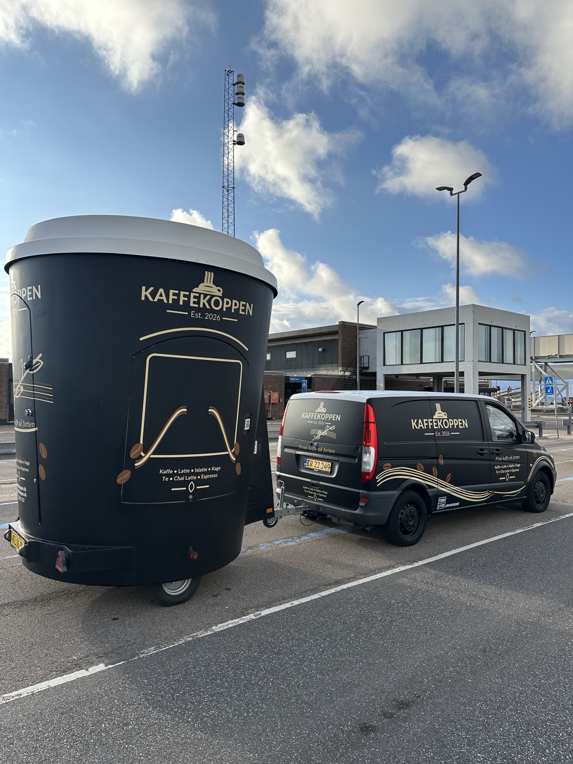 Kaffekoppens sorte kaffevogn formet som en stor kop med hvidt låg og virksomhedens logo.